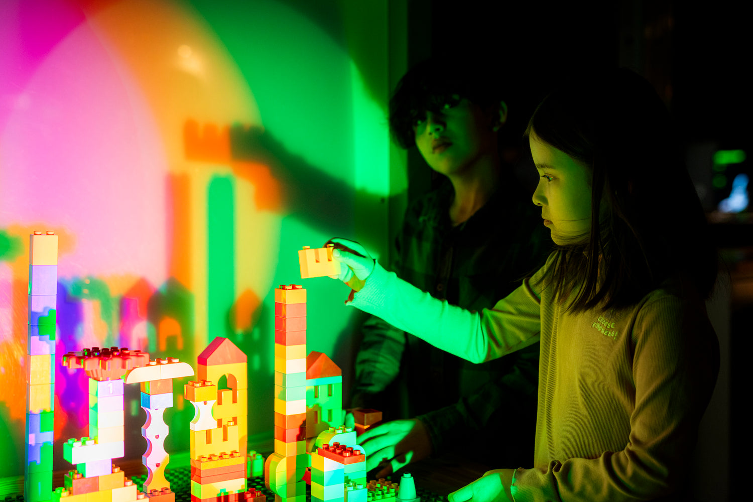 A girl and a boy are building with Lego bricks.