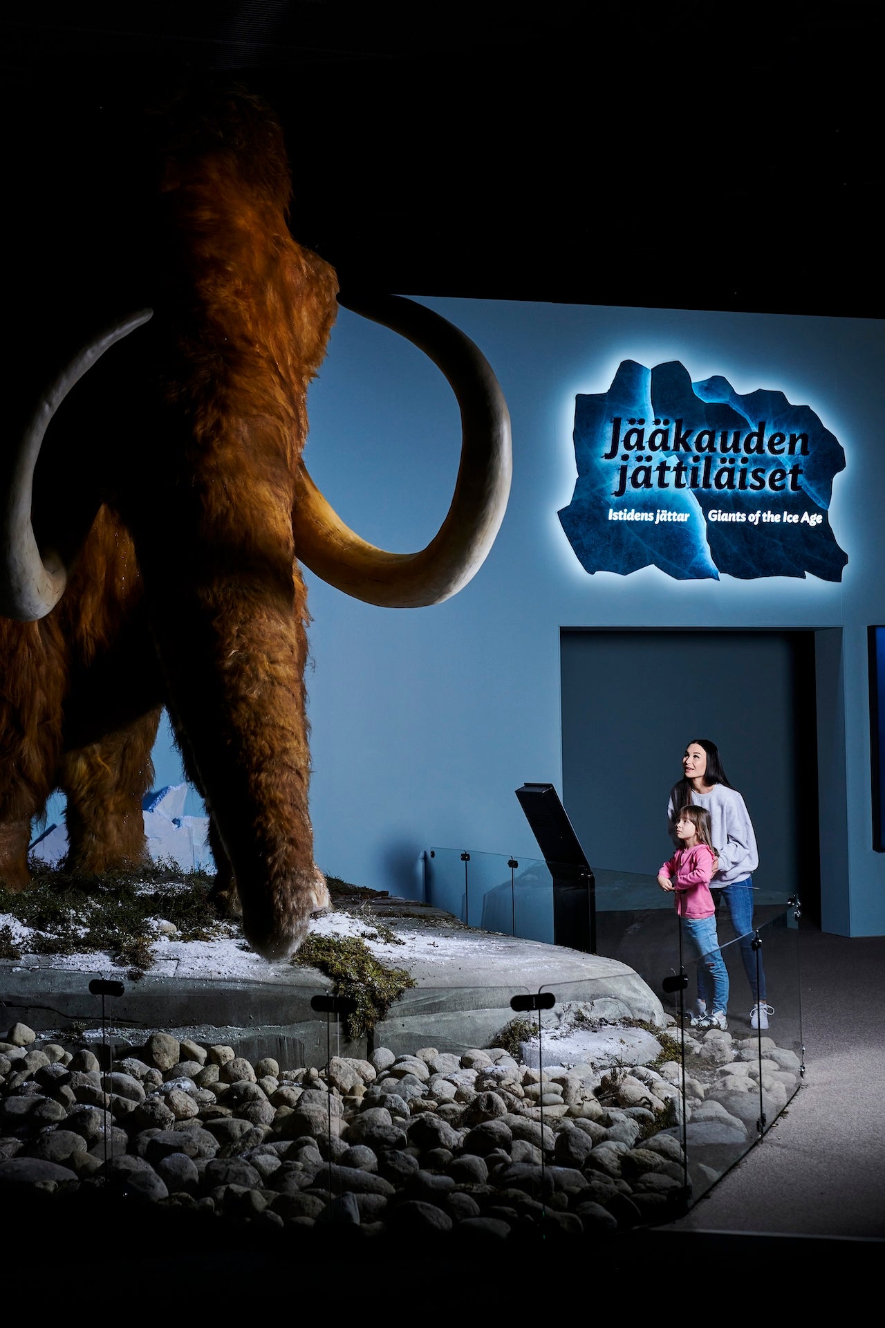 A woman and a girl looking at a mammoth in the Giants of the Ice Age exhibition.