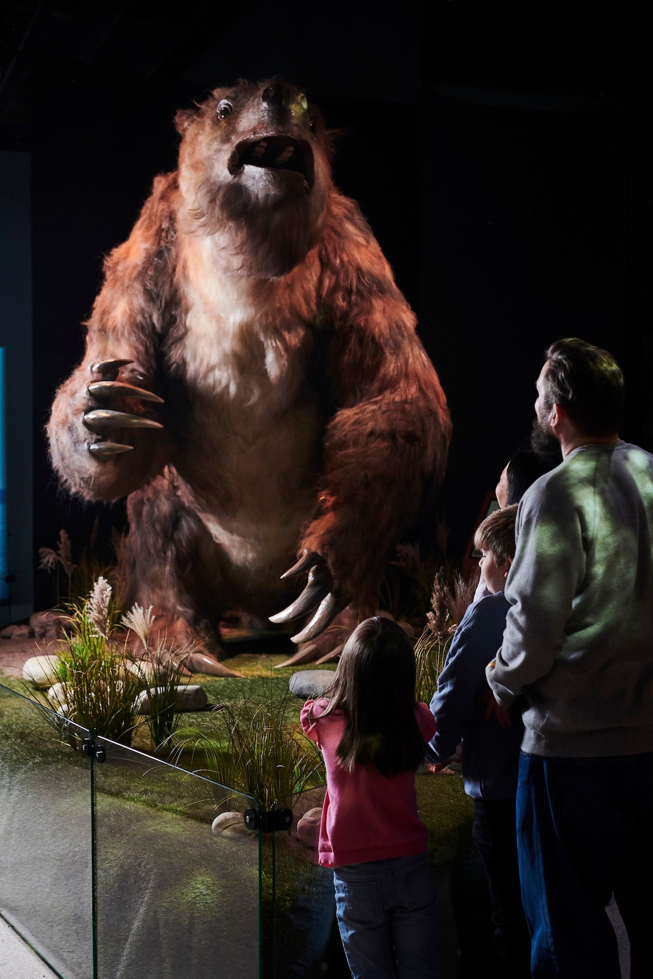 A family looking at a giant sloth in the Giants of the Ice Age exhibition.