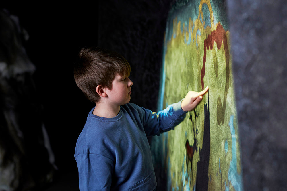 A school-aged boy drawing a rock painting.