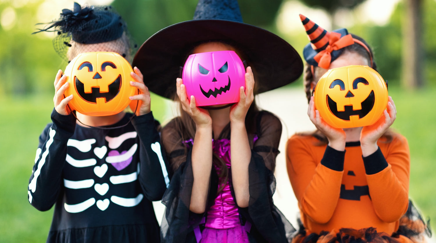 Kolme lasta Halloween-puvuissa.