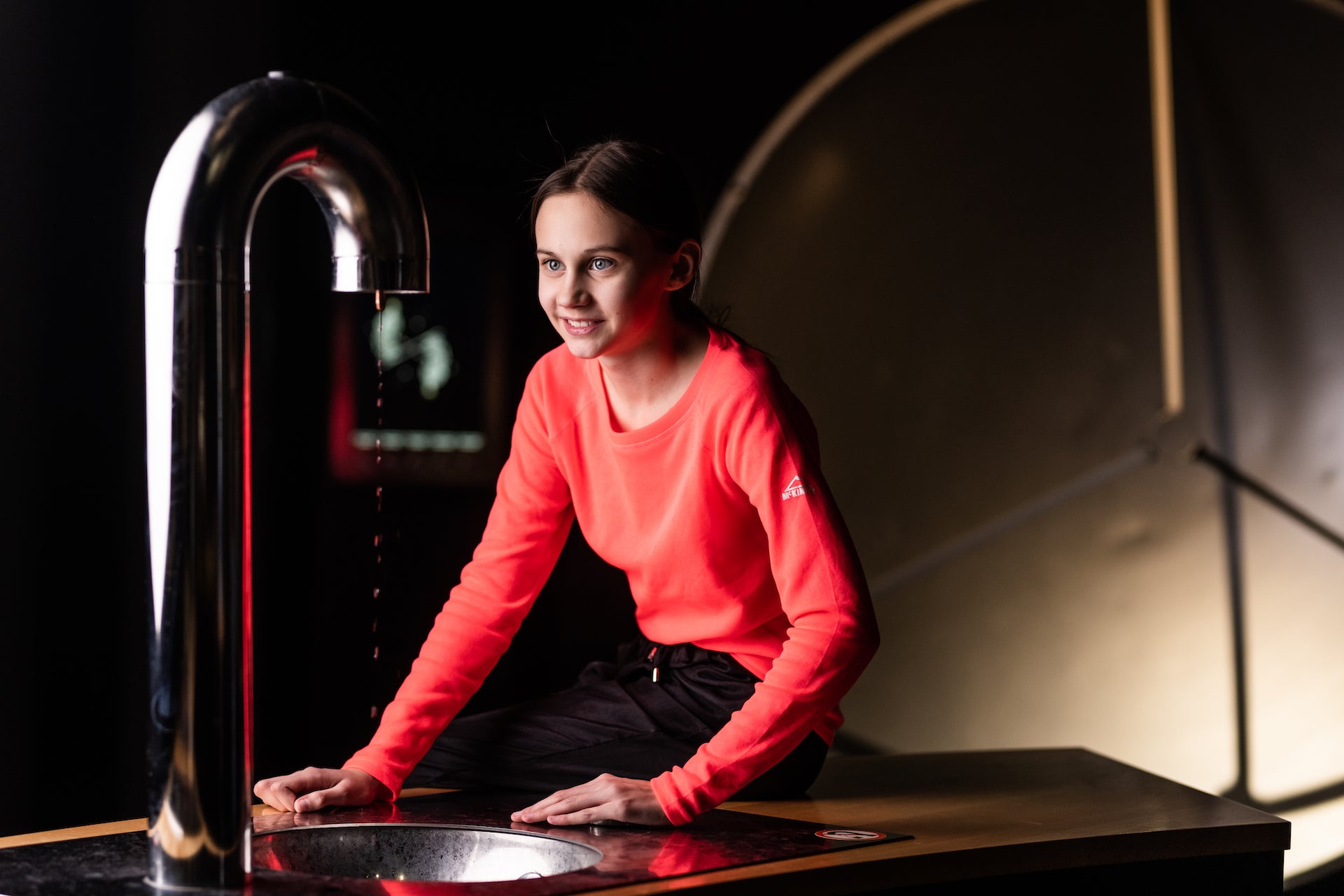 Heureka-klassikoiden näytellykohteella tyttö katselee metallista suurta "hanaa", josta tippuu vesipisaroita.