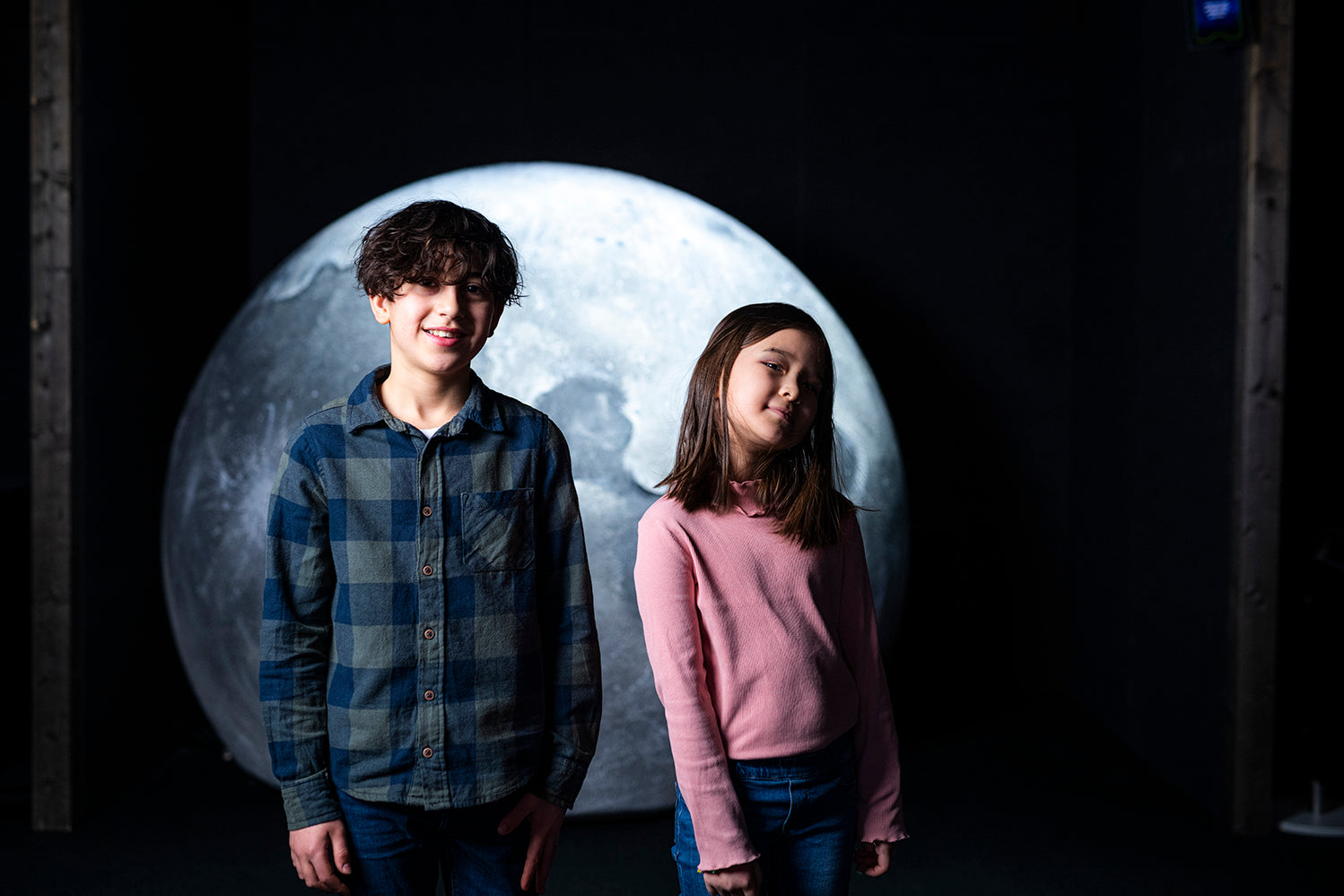 I Heurekas utställning Journey Vår resa i rymden står en flicka och en pojke framför en stor måne.