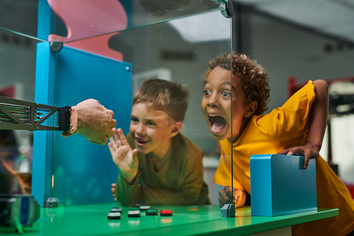 Leende barn på Heurekas AI-utställningens sten-sax-påse sajt.