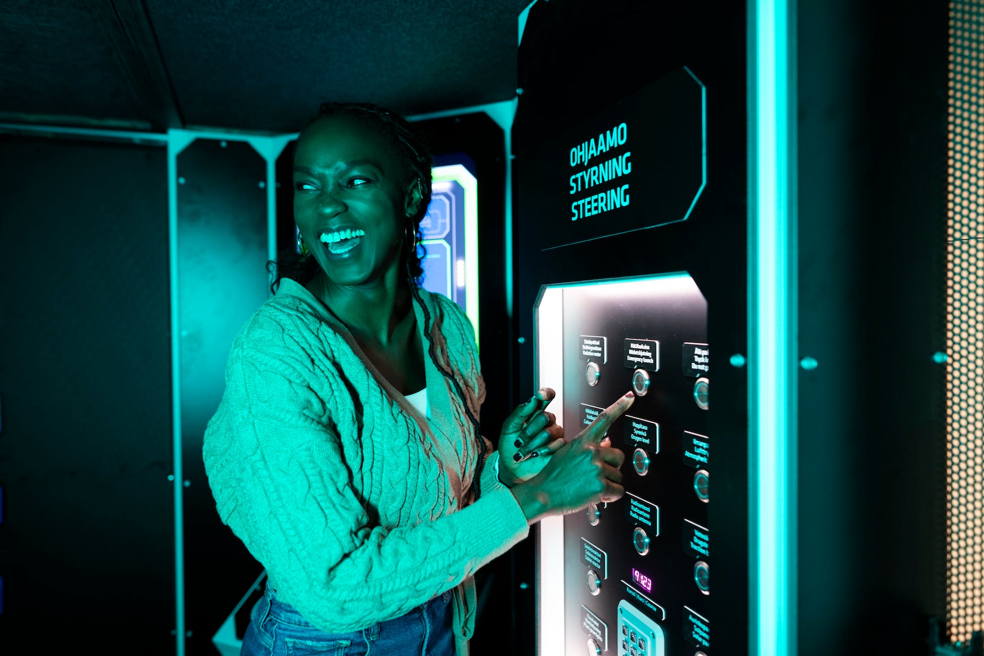 Naurava nainen painaa nappia Matkalla avaruudessa -näyttelyssä.