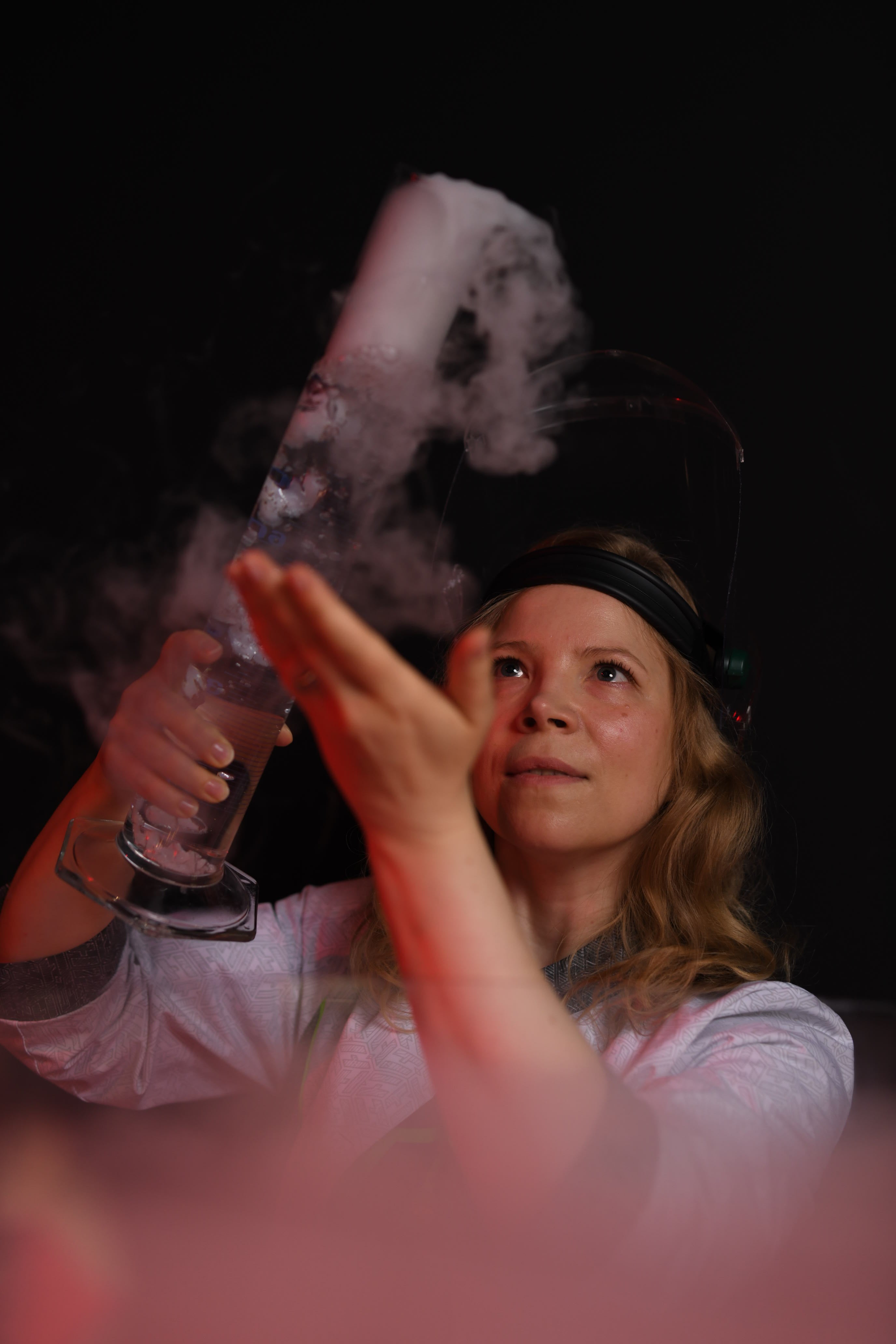 Kuvassa Heurekan innoittaja, joka pitää kädessään korkeaa lasista koepulloa, josta savuaa ulos nestemäistä typpeä. 